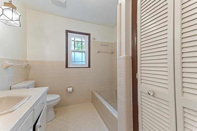 full bath with vanity, tile walls, toilet, a wainscoted wall, and a closet
