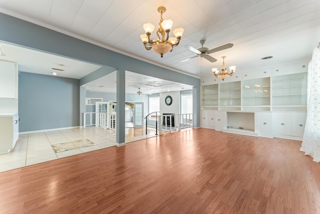 unfurnished living room featuring crown molding, ceiling fan with notable chandelier, and light wood finished floors