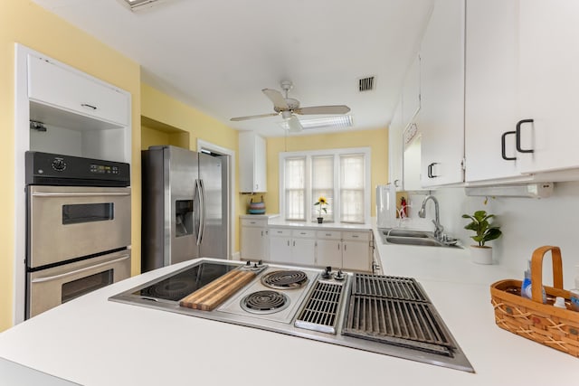 kitchen with a sink, white cabinetry, light countertops, and appliances with stainless steel finishes