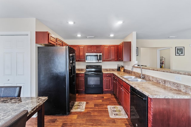 kitchen with dark wood-type flooring, kitchen peninsula, sink, and black appliances