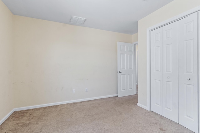 unfurnished bedroom with light colored carpet and a closet