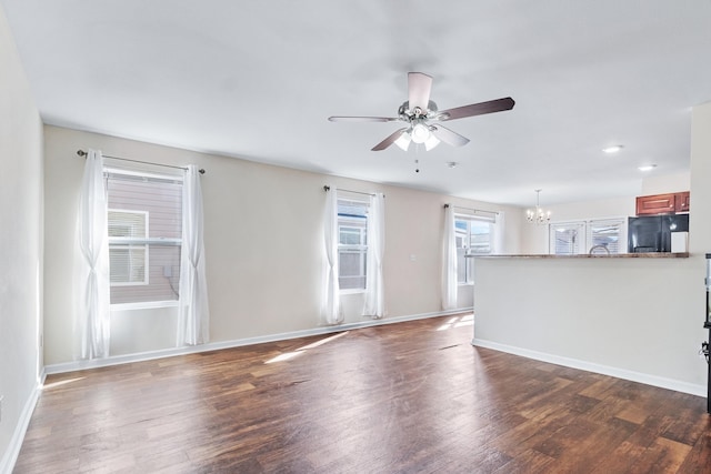 unfurnished living room with dark hardwood / wood-style flooring and ceiling fan with notable chandelier