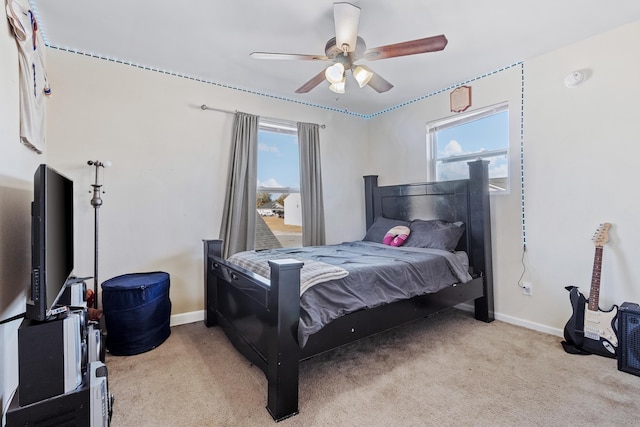 bedroom with ceiling fan, multiple windows, and light carpet