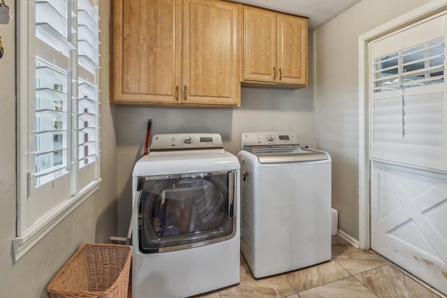 clothes washing area with separate washer and dryer and cabinet space