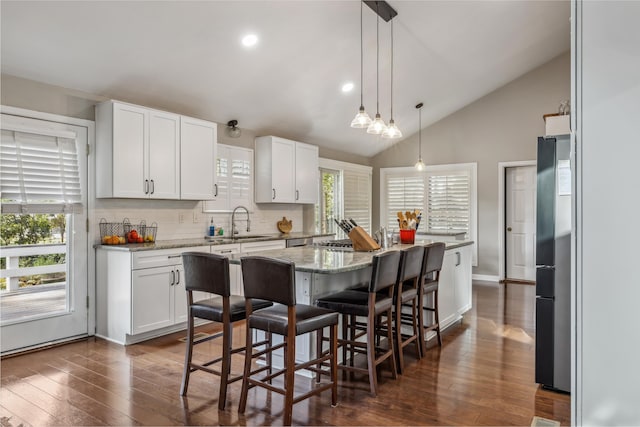 kitchen with white cabinets, a center island, freestanding refrigerator, and a sink