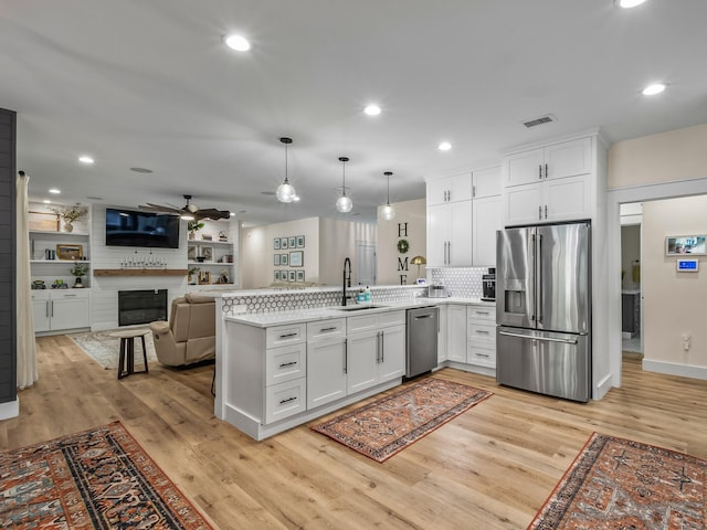 195 Coe Landing Rd, Tallahassee, FL 32310 - kitchen featuring stainless steel appliances, light countertops, white cabinets, a sink, and a peninsula