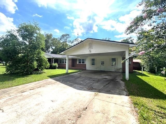 back of property with a lawn and a carport