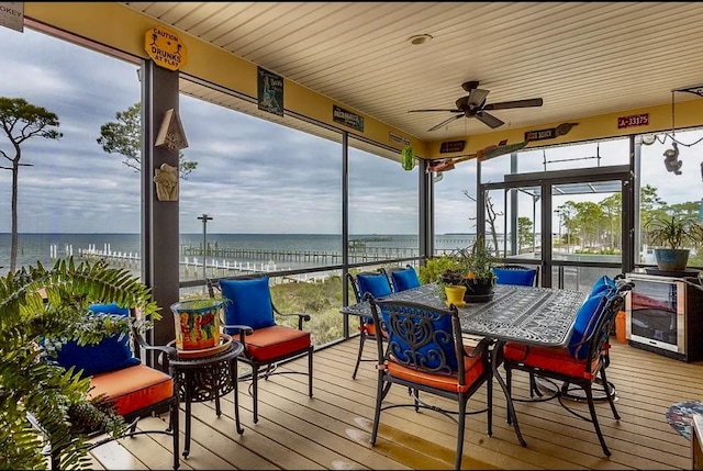 sunroom featuring beverage cooler, ceiling fan, and a water view