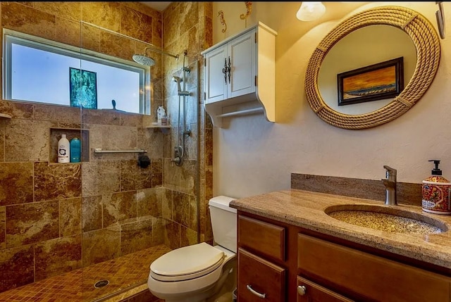 bathroom with vanity, toilet, and tiled shower