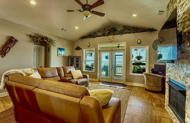 living room featuring a stone fireplace, lofted ceiling, ceiling fan, and french doors