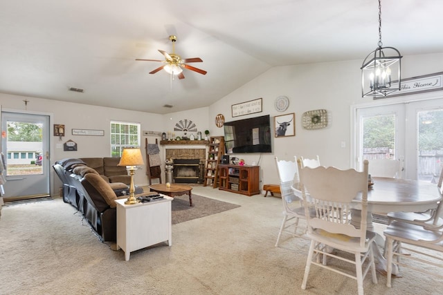 carpeted living room with ceiling fan with notable chandelier and vaulted ceiling