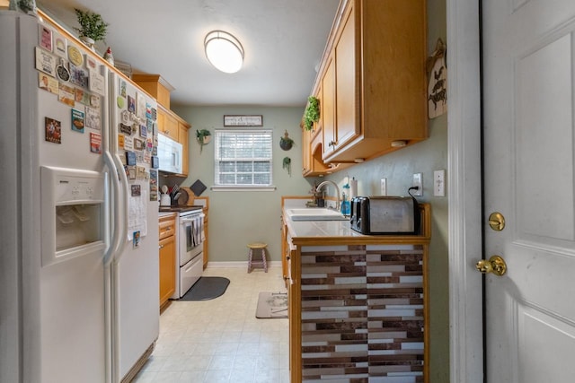 kitchen with light brown cabinets, white appliances, and sink