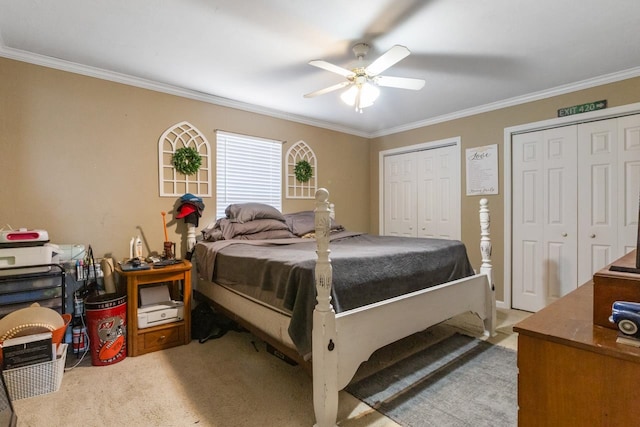 carpeted bedroom featuring multiple closets, ceiling fan, and crown molding