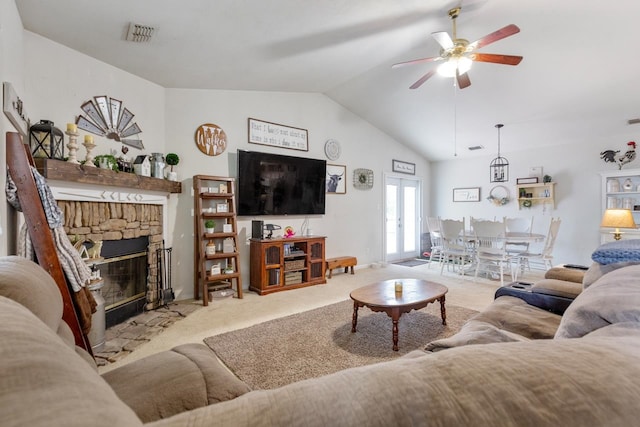 carpeted living room featuring a stone fireplace, ceiling fan, and vaulted ceiling