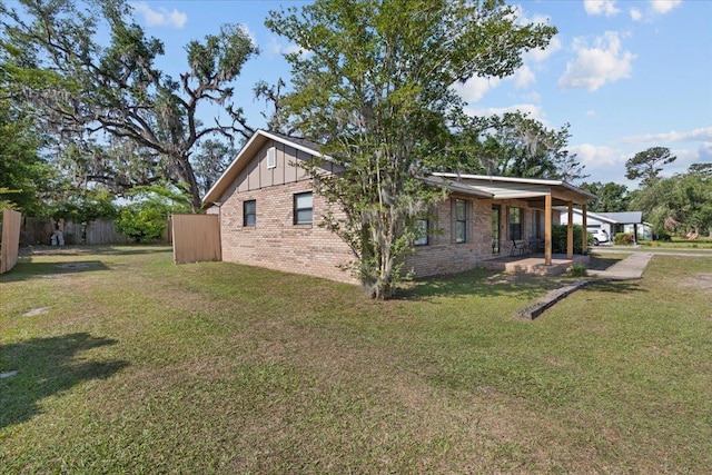 127 E Nancy St, Perry, FL 32347 - view of home's exterior with brick siding, fence, board and batten siding, and a lawn