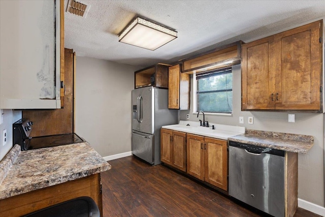 127 E Nancy St, Perry, FL 32347 - kitchen with dark wood finished floors, brown cabinetry, appliances with stainless steel finishes, a sink, and baseboards