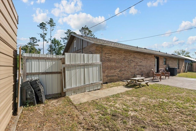 127 E Nancy St, Perry, FL 32347 - view of side of property featuring a patio, central AC unit, a yard, brick siding, and fence