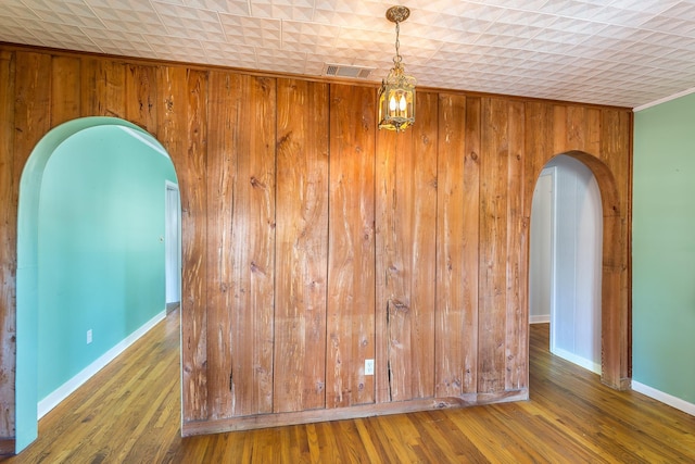 253 Prado St, Apalachicola, FL 32320 - spare room with arched walkways, wood walls, wood finished floors, and baseboards