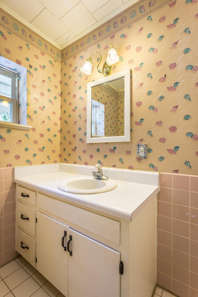 253 Prado St, Apalachicola, FL 32320 - bathroom featuring wallpapered walls, tile patterned floors, tile walls, vanity, and a wainscoted wall