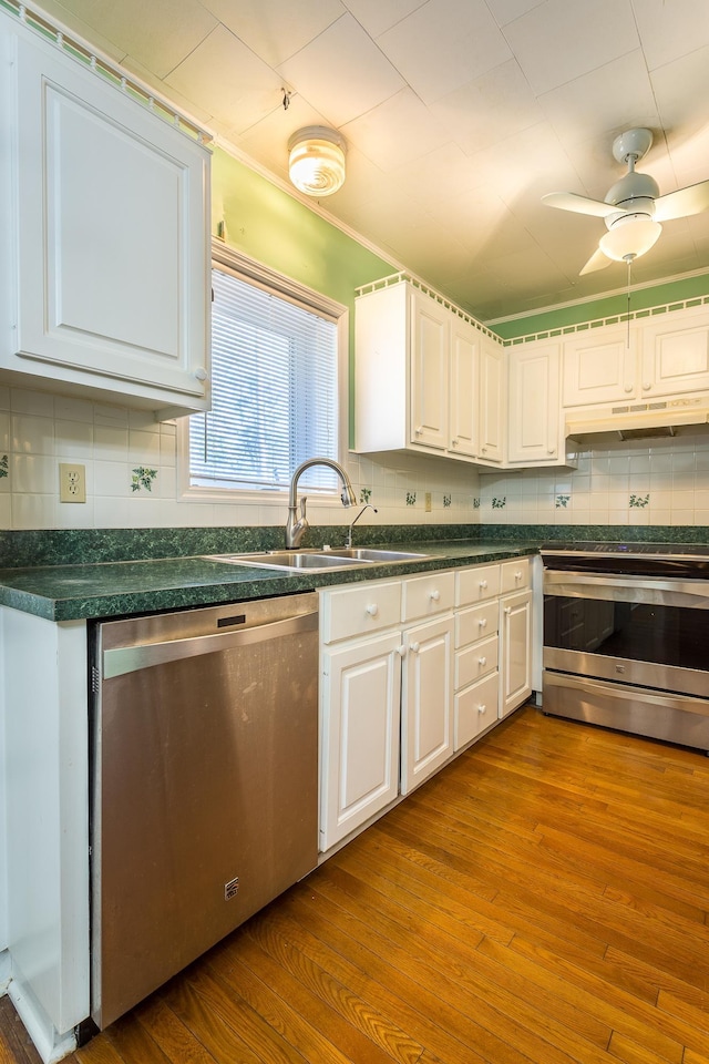 253 Prado St, Apalachicola, FL 32320 - kitchen with stainless steel appliances, a sink, under cabinet range hood, and white cabinetry
