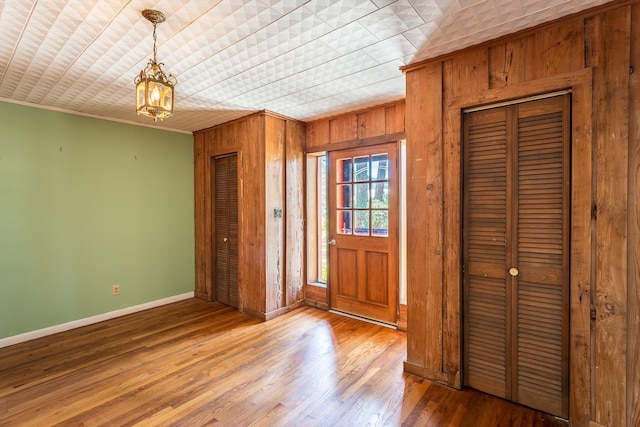253 Prado St, Apalachicola, FL 32320 - foyer entrance featuring baseboards, ornamental molding, wooden walls, a chandelier, and wood finished floors