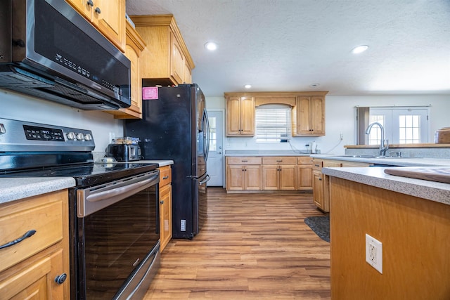 kitchen featuring a textured ceiling, stainless steel appliances, french doors, light hardwood / wood-style floors, and sink