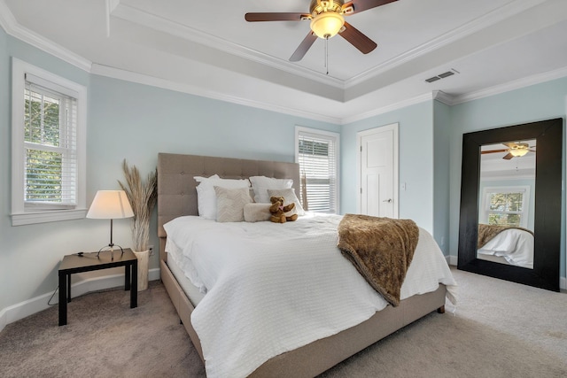 bedroom with a tray ceiling, visible vents, carpet flooring, and multiple windows