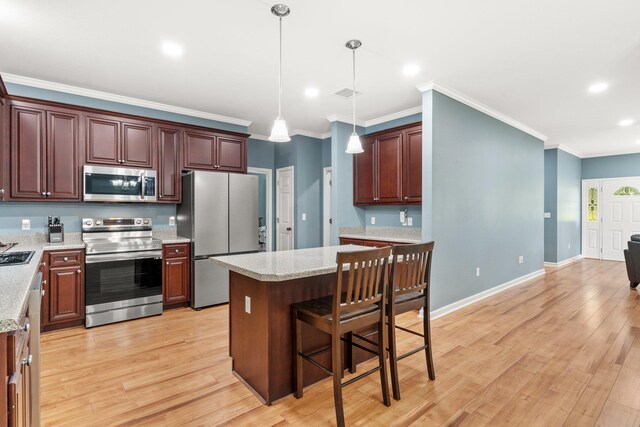 1094 Paul Thompson Rd, Monticello, FL 32344 - kitchen featuring appliances with stainless steel finishes, crown molding, decorative light fixtures, a breakfast bar, and light wood finished floors