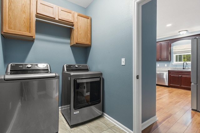 1094 Paul Thompson Rd, Monticello, FL 32344 - washroom featuring cabinet space, independent washer and dryer, baseboards, and light wood-type flooring