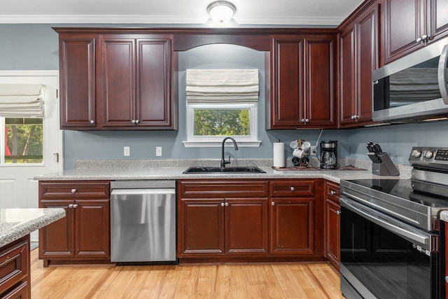 1094 Paul Thompson Rd, Monticello, FL 32344 - kitchen with stainless steel appliances, a sink, reddish brown cabinets, light wood-style floors, and crown molding