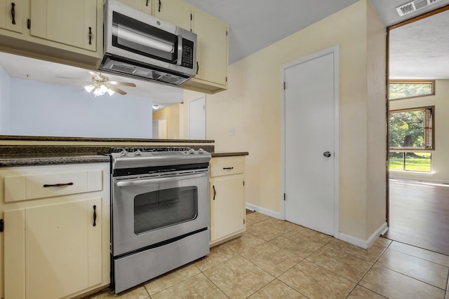 4054 Mcleod Dr, Tallahassee, FL 32303 - kitchen with appliances with stainless steel finishes, dark countertops, cream cabinets, and light tile patterned floors