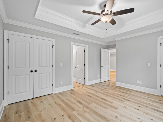 unfurnished bedroom with light wood-type flooring, a raised ceiling, ceiling fan, and crown molding