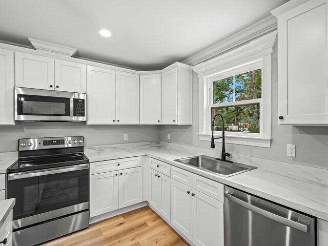 kitchen featuring light stone counters, stainless steel appliances, sink, light hardwood / wood-style floors, and white cabinets