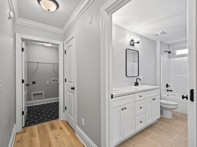 full bathroom with hardwood / wood-style flooring, shower / tub combination, ornamental molding, vanity, and toilet