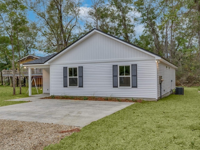 rear view of house featuring central air condition unit, a yard, and a carport