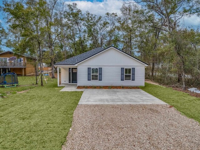 view of front of home featuring a trampoline, a front lawn, and a patio