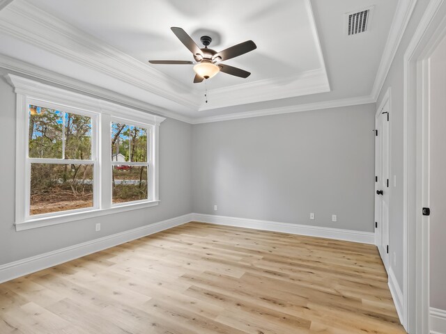 unfurnished room featuring ornamental molding, light hardwood / wood-style floors, ceiling fan, and a raised ceiling