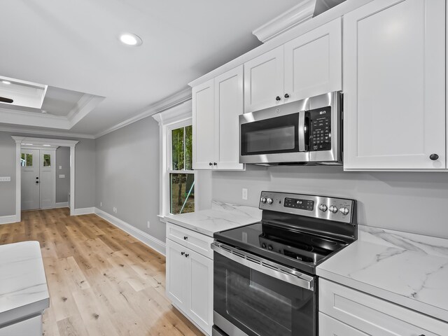 kitchen featuring light stone counters, appliances with stainless steel finishes, ornamental molding, white cabinets, and light wood-type flooring