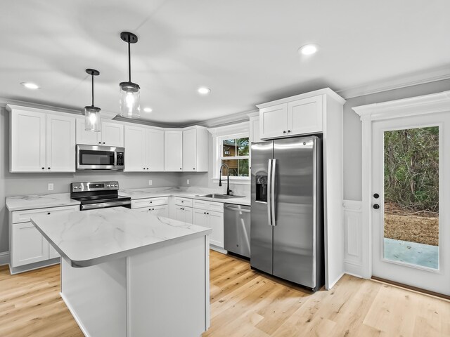 kitchen with stainless steel appliances, white cabinetry, decorative light fixtures, sink, and light hardwood / wood-style flooring