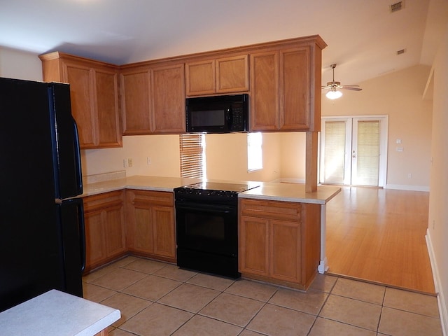 kitchen with french doors, black appliances, vaulted ceiling, light tile patterned floors, and kitchen peninsula