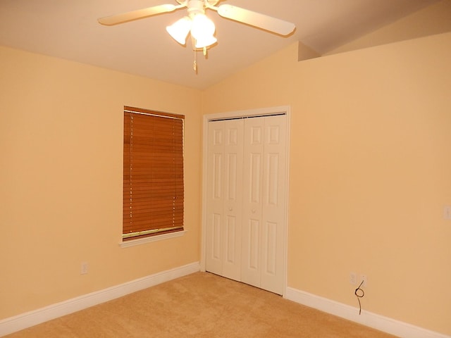 unfurnished bedroom featuring ceiling fan, a closet, carpet floors, and vaulted ceiling