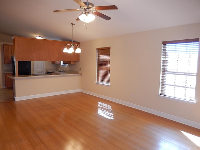 kitchen with sink, light hardwood / wood-style flooring, kitchen peninsula, decorative light fixtures, and ceiling fan with notable chandelier