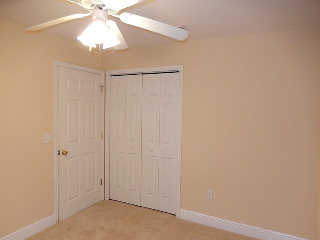 unfurnished bedroom featuring ceiling fan, light carpet, and a closet