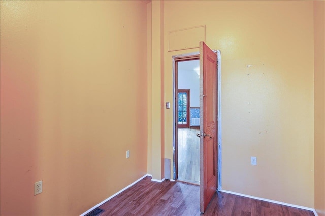 unfurnished room featuring wood finished floors, visible vents, and baseboards