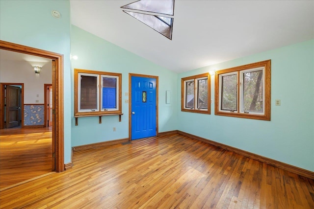 spare room with light wood-style floors, vaulted ceiling, and baseboards