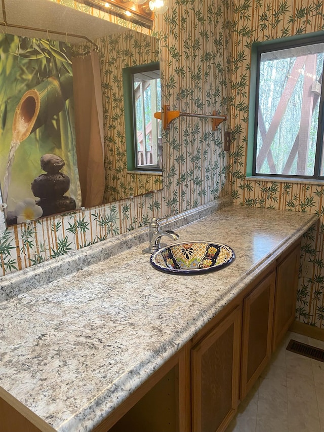 bathroom featuring tile patterned flooring, visible vents, vanity, and wallpapered walls