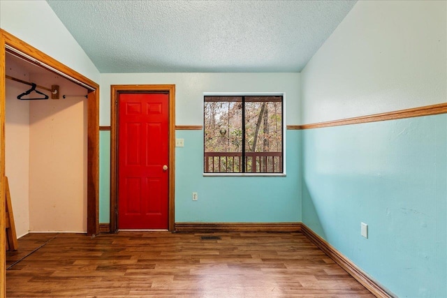 entryway with a textured ceiling, baseboards, and wood finished floors