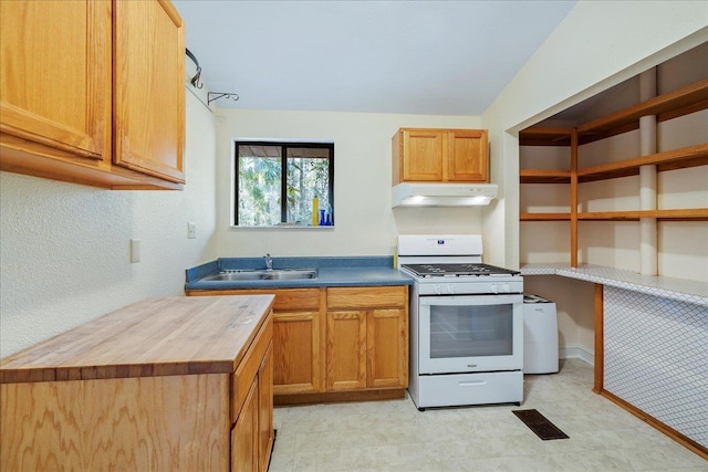 kitchen featuring white gas stove, visible vents, a sink, wood counters, and under cabinet range hood