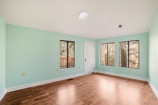 unfurnished room with a healthy amount of sunlight, visible vents, and baseboards