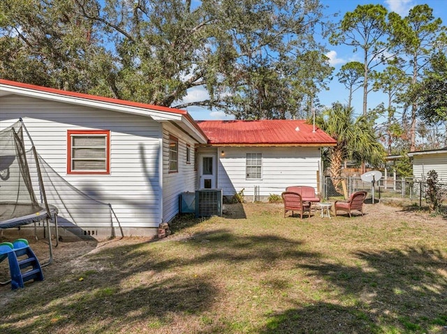 back of property featuring a trampoline, a yard, and central air condition unit